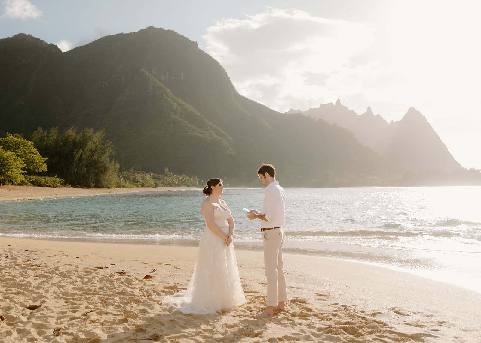 bride and groom read vows on tunnel's beach in kauai hawaii