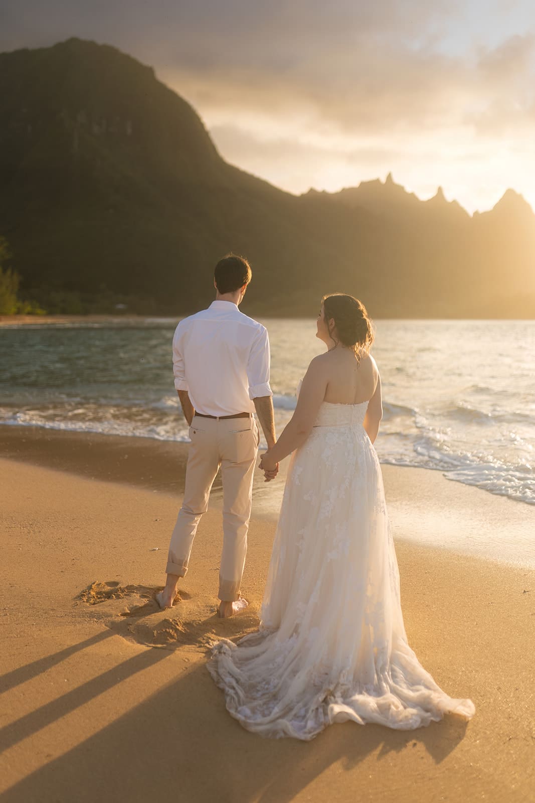 bride and groom stand on the sand on tunnel's beach in kauai