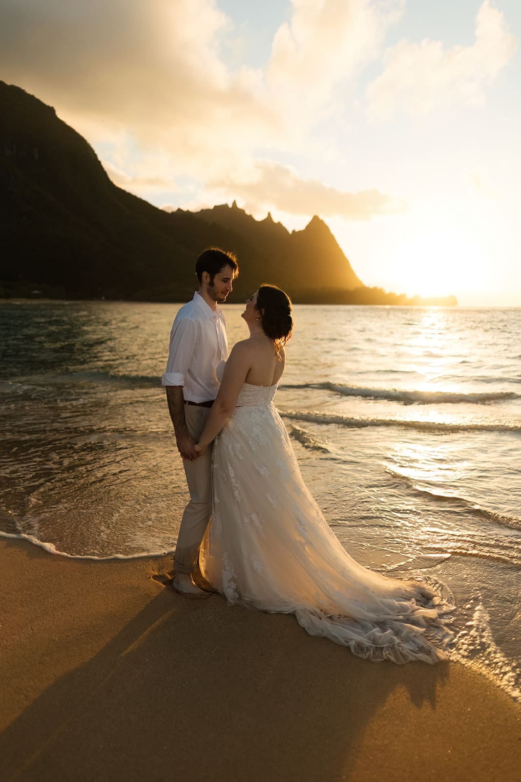 bride and groom stand in the waves on tunnel's beach in kauai hawaii