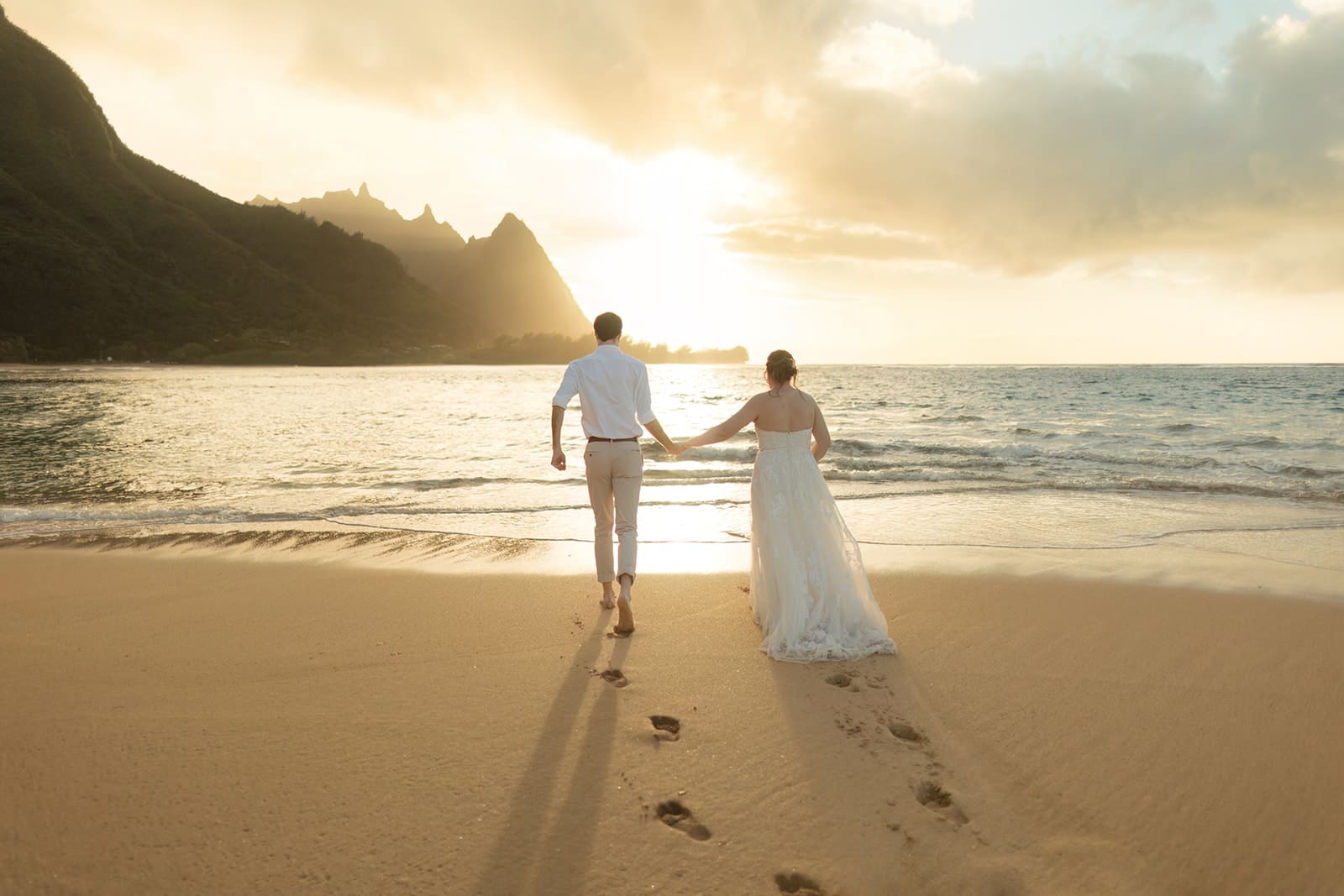 bride and groom run in the waves on tunnel's beach in kauai