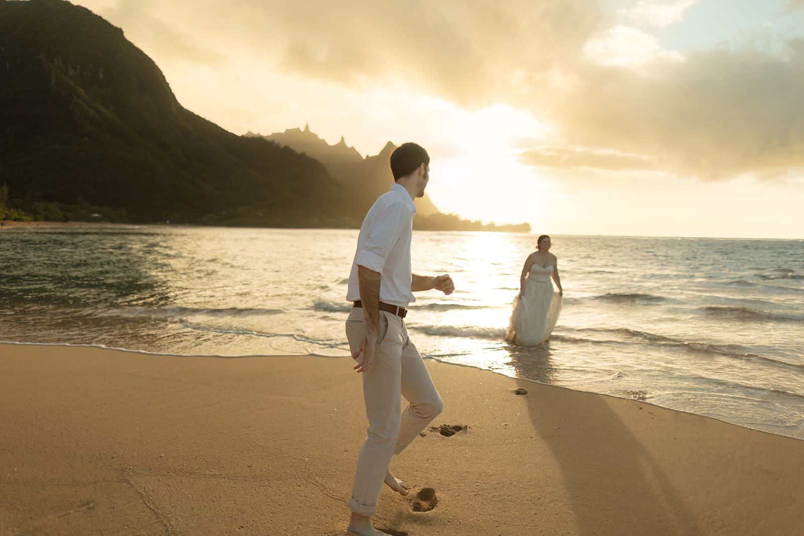 bride and groom run in the waves on tunnel's beach in kauai Hawaii