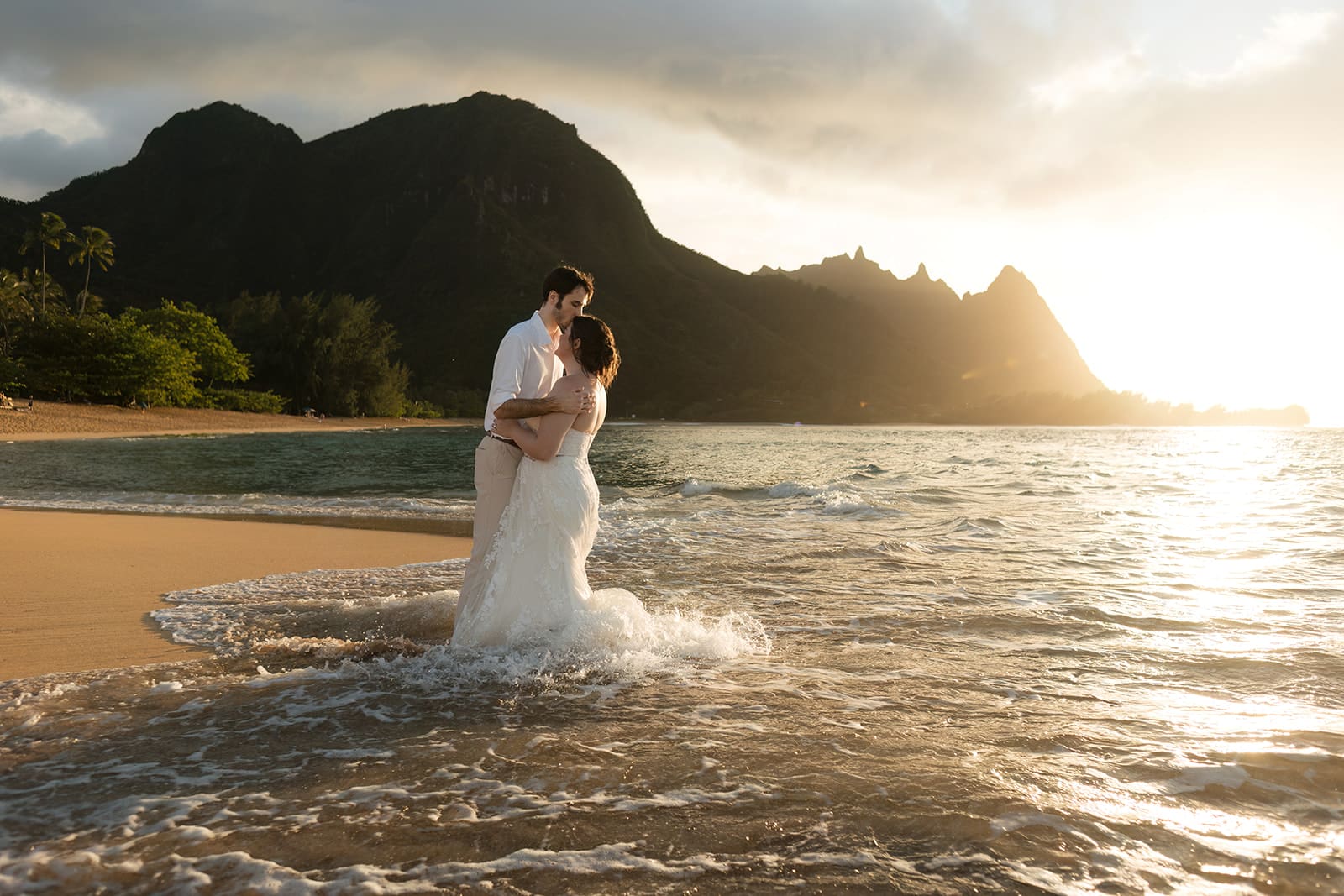 beach in kauai elopement hawaii an unforgettable evening complete with backlit rain, a stunning rainbow, light beams, and a colorful golden sunset.